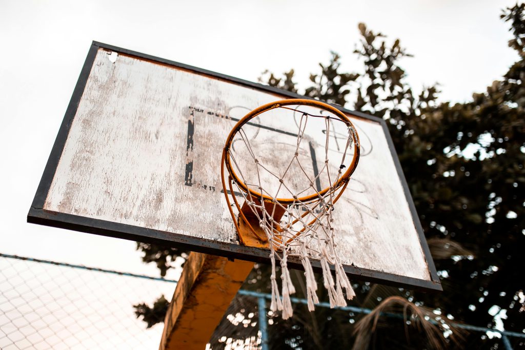 Low angle shot of an outdoor basketball hoop with a weathered backboard, perfect for sports themes.