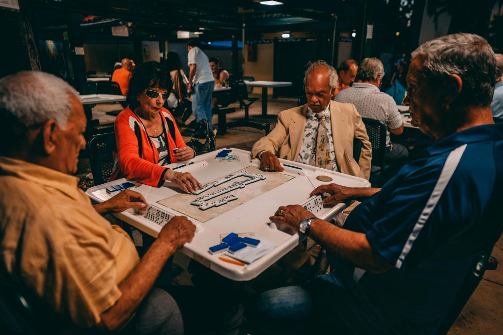 Group of senior adults engaged in an outdoor game of Mahjong in Miami, Florida.